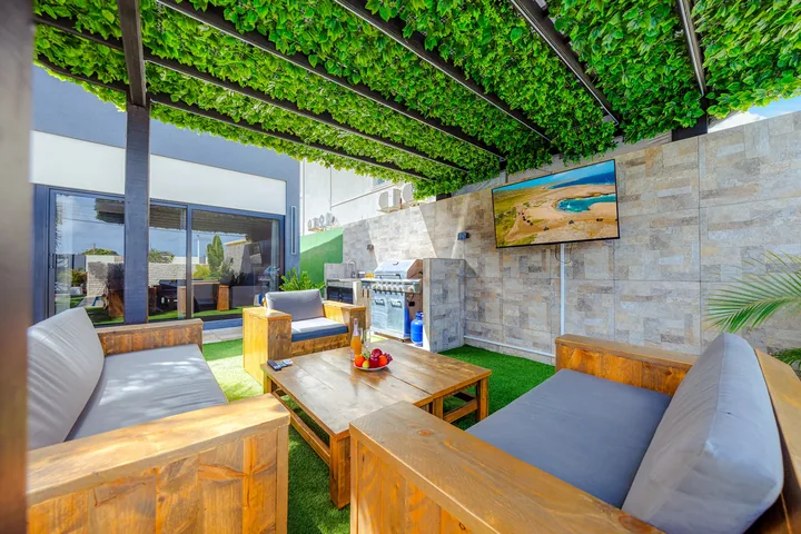 Outdoor shaded lounge with wooden seating and barbecue